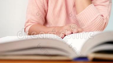 合上女`的手翻书页，在图书馆看书时，她的手指沿着书页移动。 有选择的焦点。